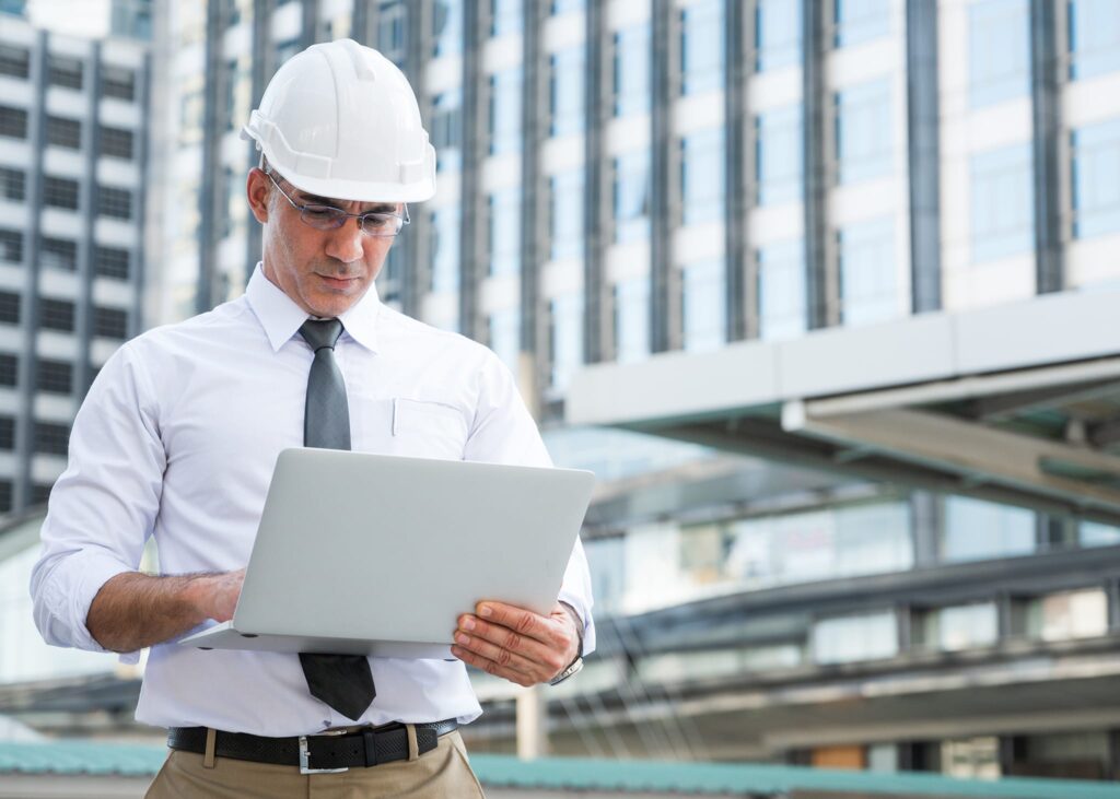 Civil engineering using laptop while working on building construction site e1600398145446